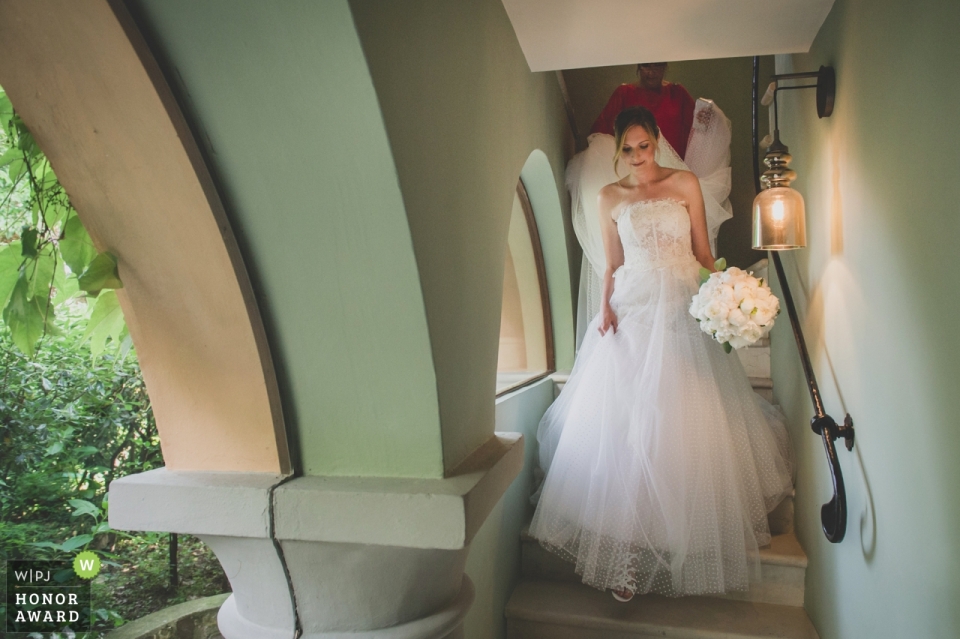 Foto por: <a href="https://www.wpja.com/contests/2018-v17-photography-competition/best-wedding-photographers/2338771"> Alessandro Vargiu - Torino </a> Imagen de fotoperiodismo de bodas de una novia bajando escaleras en Albereta Relais & Châteaux