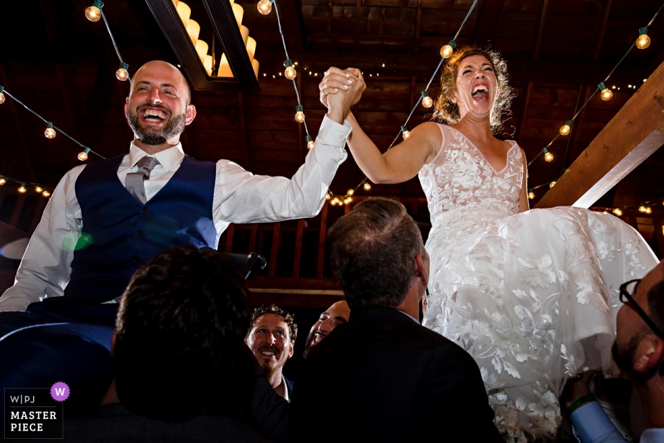 Image de la mariée et le marié a soulevé pour la danse Horah lors de leur réception au Linekin Bay Resort Boothbay Harbor Maine La mariée et le marié sont levés pour la danse Horah lors de leur réception | Linekin Bay Resort Boothbay Harbor dans le Maine