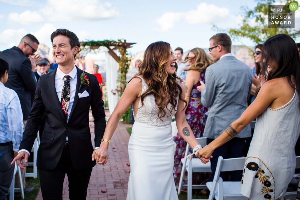 Photo by: <a href="https://www.wpja.com/contests/2018-v20-photography-competition/best-wedding-photographers/2406886">Rebekah Sampson - Payson Arizona</a> Sedona Sky Ranch Lodge, Sedona AZ - wedding photojournalism image of a couple celebrating with guests as they walk out after ceremony