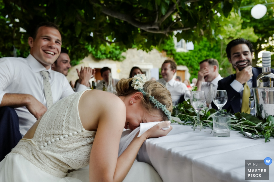 Photo by: <a href="https://www.wpja.com/contests/2019-v08/best-wedding-photographers/2512121">William Lambelet - Montpellier </a> The guests and bride cannot stop laughing during a funny speech at her Chateau du Puits es Pratx, Ginestas wedding in this award-winning photo by a Montpellier, France wedding photographer.
