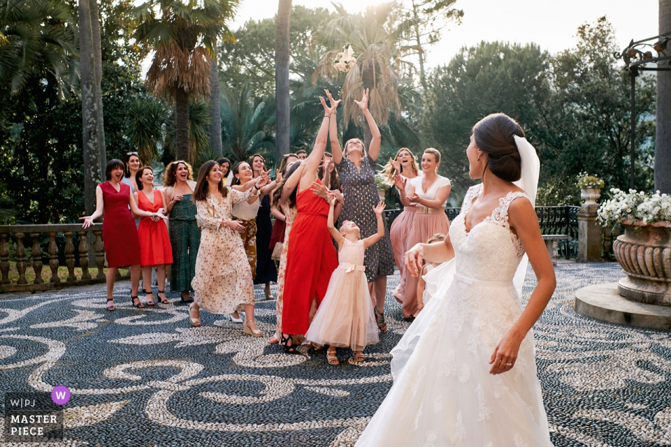 The bride tosses her bouquet outside the Villa Durazzo in this wedding image composed by a Savona, Liguria photographer. 