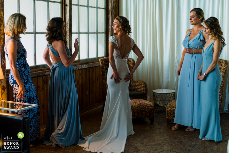 Photos du lieu de mariage de Sodo Park Seattle WA | Demoiselle d'honneur donnant le bon signe à la mariée après s'être habillée.