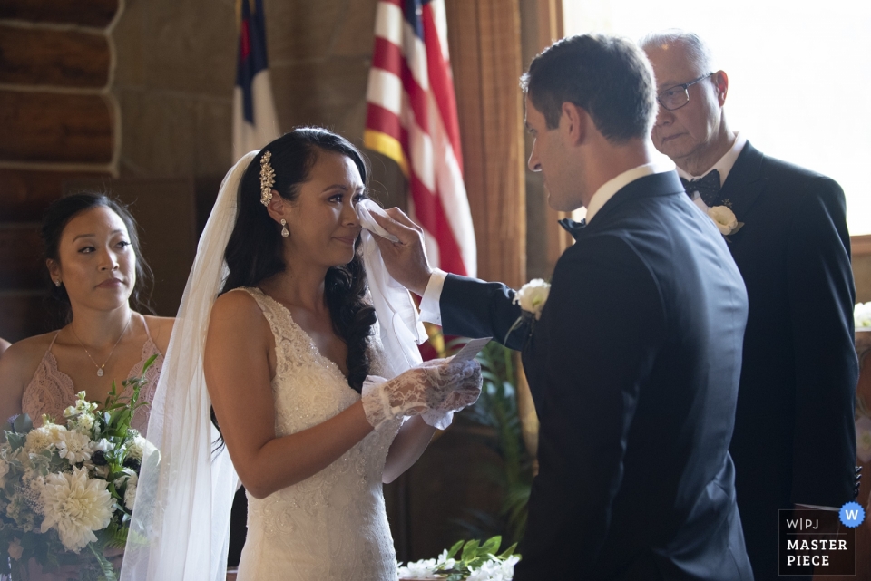 Capela dos soldados, fotógrafo de casamento em Big Sky Montana | Para surpresa da noiva, o noivo produz um lenço para enxugar as lágrimas do rosto da noiva.