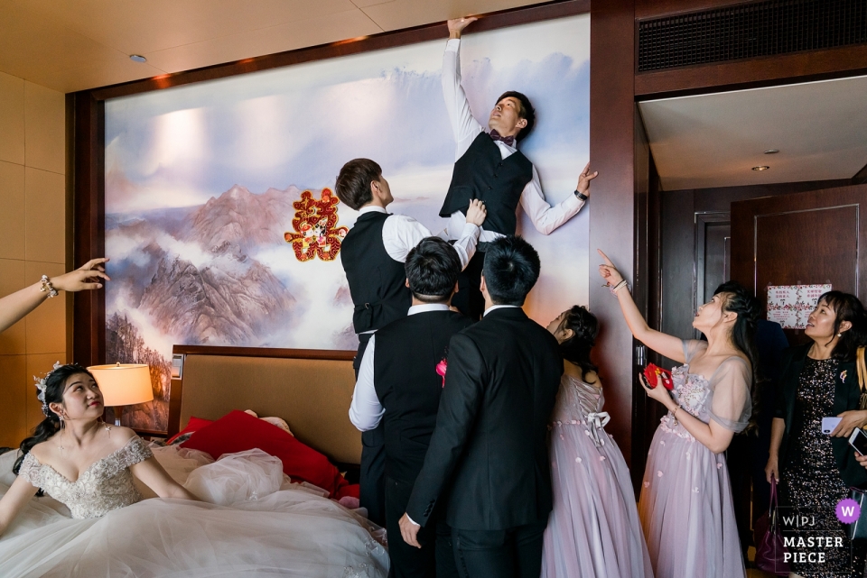 Marié à la recherche des chaussures de la mariée pendant les jeux de porte Photographie du jour du mariage à l'aile du sommet mondial de Beijing Shangri-La China - Photo du marié à la recherche des chaussures de la mariée