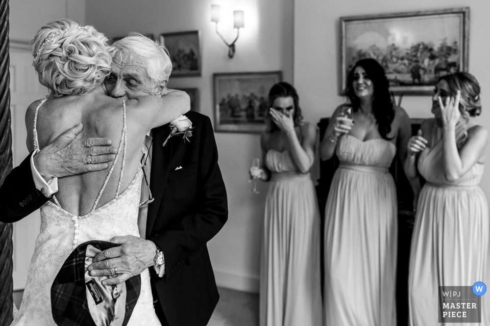 Photo: <a href="https://www.wpja.com/contests/2019-v14/best-wedding-photographers/2554064"> Andy Griffiths - St. Helens Lancashire </a> Photographie de reportage sur le mariage à Iscoyd Park - Un père embrassant une demoiselle d'honneur dans le dos en pleurant