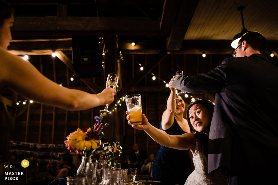 La mariée et le marié portent un toast avec leurs amis Lieu de mariage: Farmhouse Inn at Robinson Farm - Photographie du jour du mariage | Les mariés portent un toast avec leurs amis