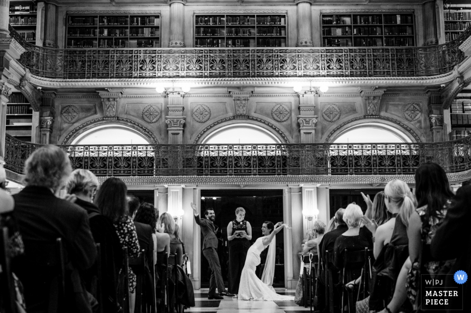 Photo by: <a href="https://www.wpja.com/contests/2019-v17/best-wedding-photographers/2563046">Kathleen Ricker - Linthicum Heights Maryland</a> Peabody Library - Baltimore MD wedding ceremony pictures of the bride and groom celebrating with arms up in the air.