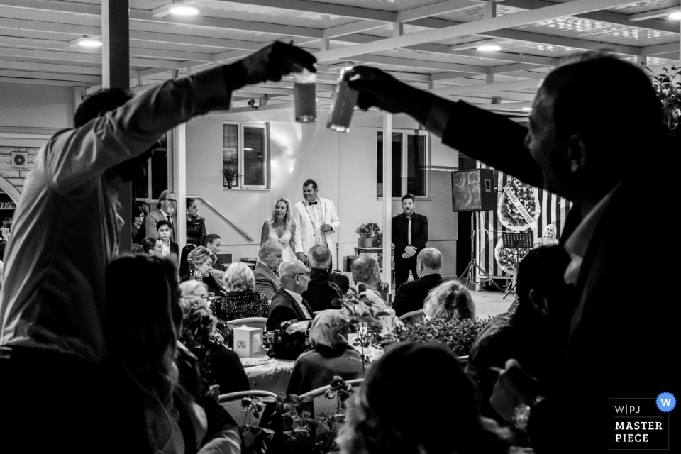 Özak Hotel, Ayvalık, Balıkesir fotografia de casamento - Os melhores homens estão brindando suas bebidas quando o casal está fazendo seus discursos.