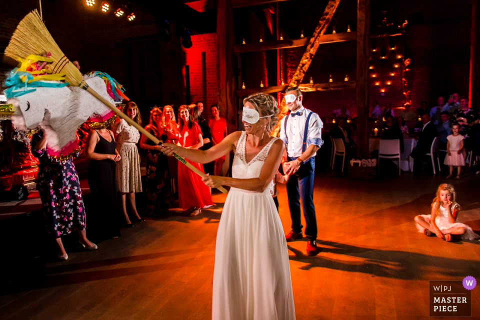 Photo: <a href="https://www.wpja.com/contests/2019-v19/best-wedding-photographers/2570290"> Philippe Swiggers - Bekkevoort </a> Image de réception de mariage Kasteel van Hoen de la mariée avec un balai frappant une pinata.