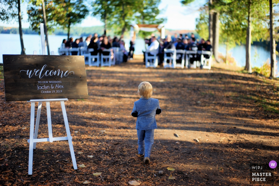 Calabogie Peaks Resort, Calabogie Ontario wedding photos : Ring bearer makes the solo walk to the outdoor ceremony under the trees at the lake.