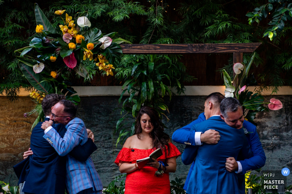 Foto do casamento em St. Michaels Restaurant, Santa Mônica, Califórnia, EUA - Dois noivos abraçam seus entes queridos