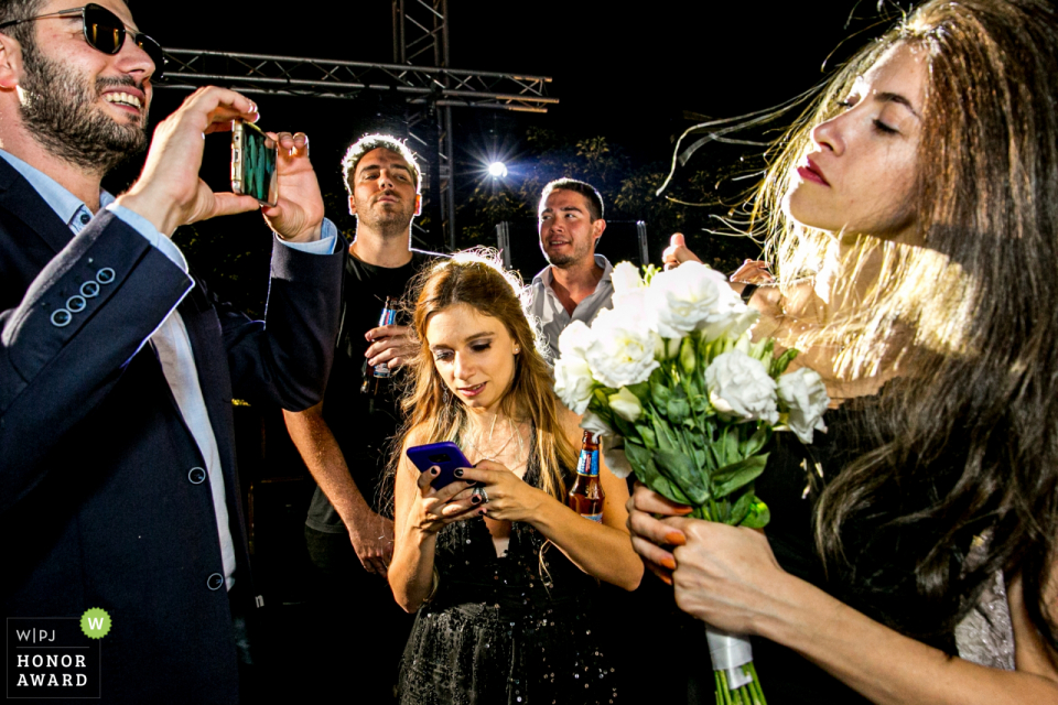 Le photographe de Wyndham Ankara a déclaré: Un garçon avec des lunettes de soleil (pendant minuit) essaie de prendre une photo de fille qui a attrapé le bouquet, un garçon regarde cette fille et un autre garçon à côté de lui regarde ce garçon et une fille joue avec son téléphone dans le milieu