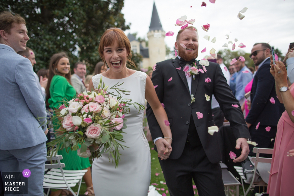 CHATEAU D'AGASSAC LUDON MEDOC CEREMONY PHOTOGRAPHY | BRIDE & GROOM SURPRISED AND AMUSED BY THE PETALS THROWING