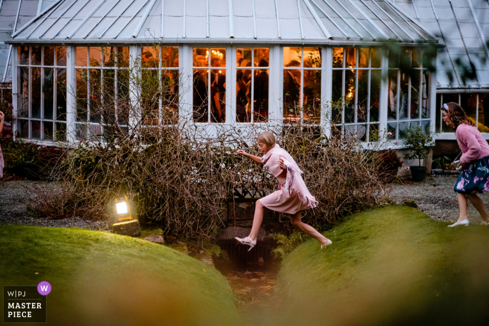 Castillo de Glenapp, Escocia Invitados a la boda durante la recepción | Niños vestidos y saltando la brecha en el jardín exterior.