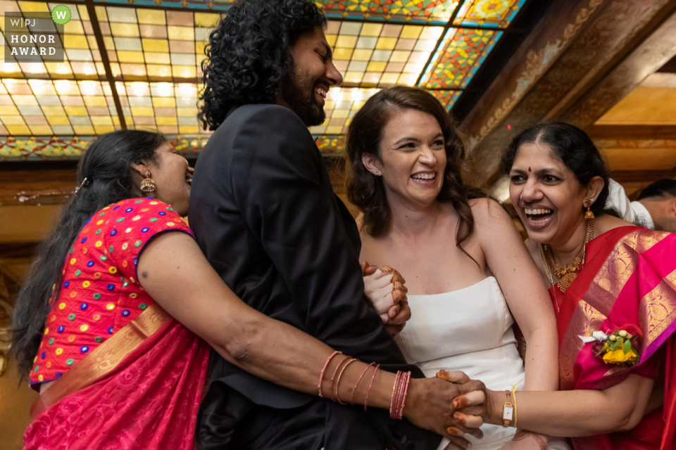 The Georgia WPJA is proud to award this non traditional and modern Atlanta wedding image at the Fox Theater of the GA grooms aunt and Mom surround the couple while dancing