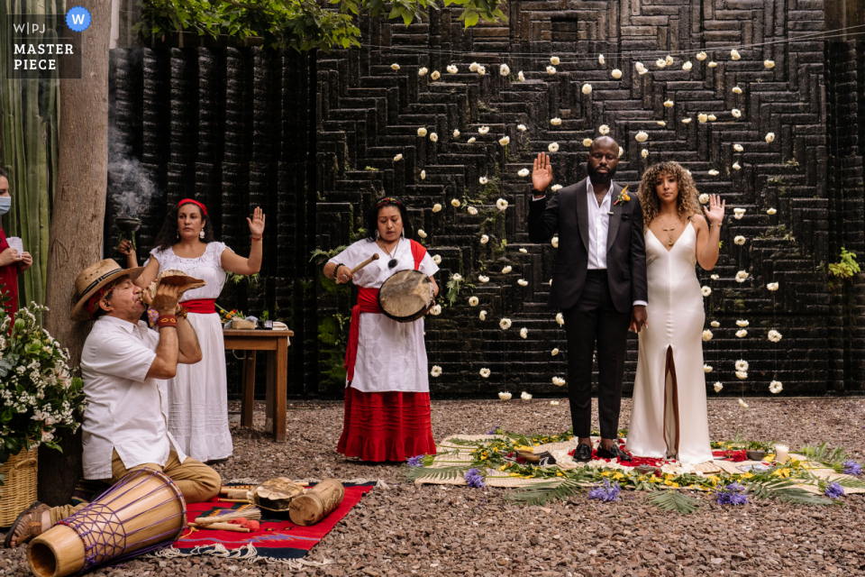 Hotel Azul, cidade de Oaxaca, imagem vencedora do prêmio de casamento ao ar livre mostrando um momento de cerimônia zapoteca Hotel Azul, imagem vencedora do prêmio de casamento ao ar livre da cidade de Oaxaca, mostrando um momento de cerimônia zapoteca. Os melhores concursos de fotos de casamento do mundo apresentados pela WPJA