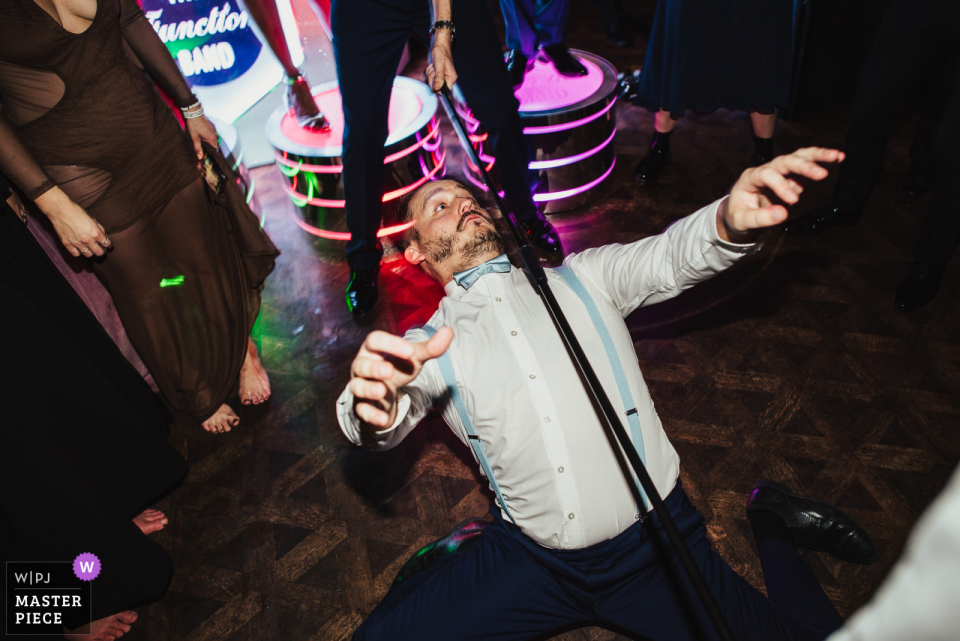 Best Devon documentary wedding photography from Huntsham Court showing A member of a wedding band performing a limbo dance at a wedding