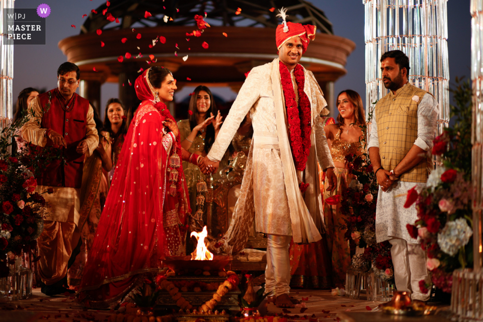 A documentary wedding photographer at the Emirates Palace event venue in Abu Dhabi, UAE captured this Bride and groom showered with flower petals during Indian ceremony