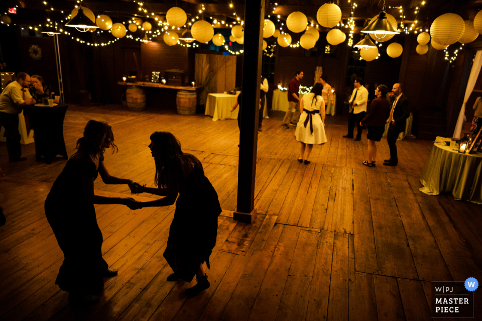 Image de la silhouette du lieu de mariage Inn at Mountain View Farm à East Burke, Vermont, de deux filles dansant pendant la réception Image de la silhouette du lieu de mariage Inn at Mountain View Farm à East Burke, Vermont, de deux filles dansant pendant la réception