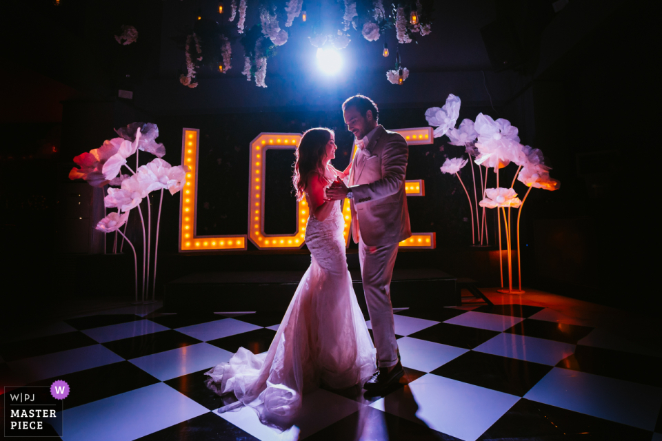 Newlyweds Share First Dance Under Glowing Stage Lights at Bosphorus Palace in Istanbul Newlyweds share their first dance under the stage lights at Bosphorus Palace in Istanbul, as they sway on the black and white checked floor.