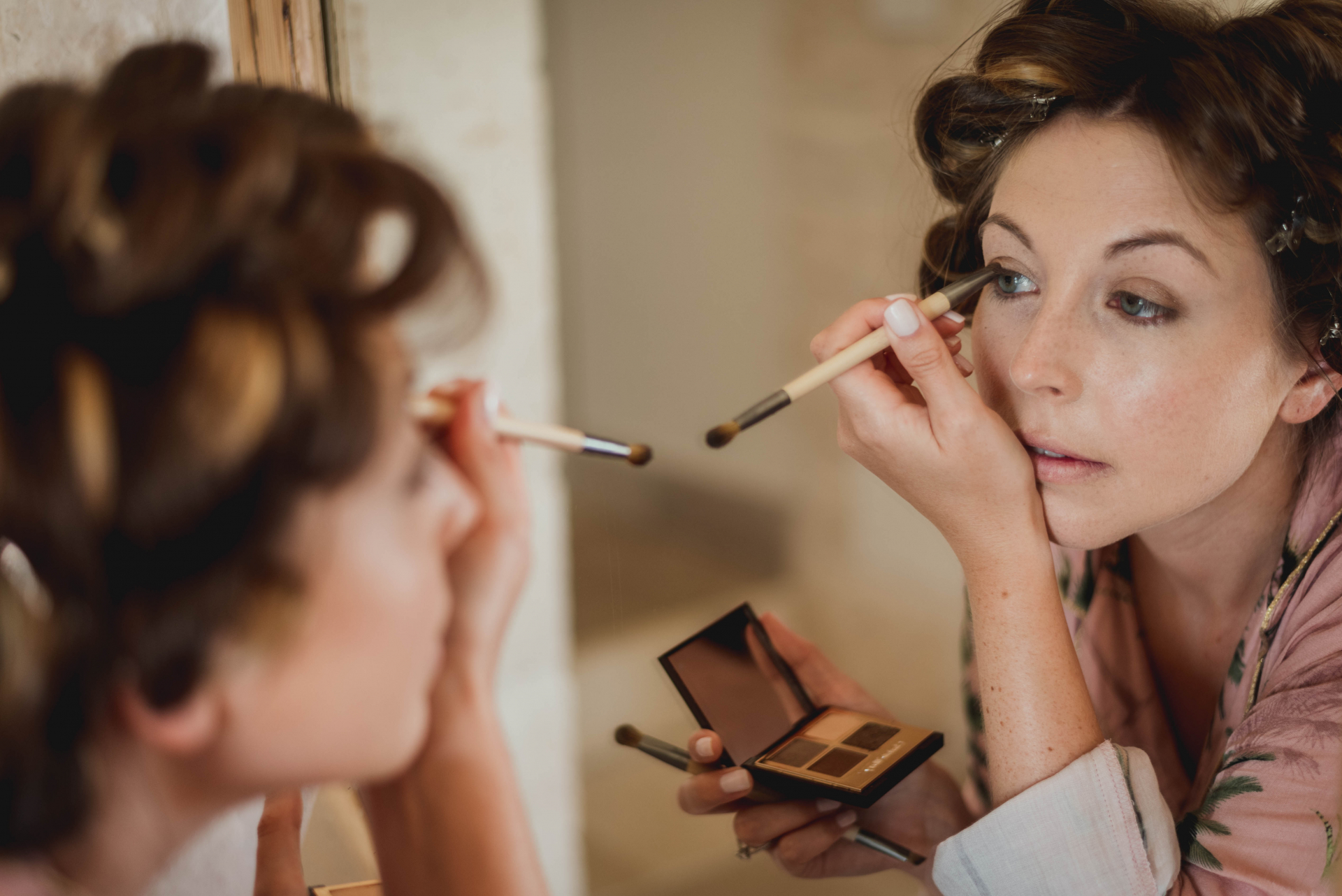 Trouwfotografie Masseria Grieco - Regio Apulië, Italië | Vóór de ceremonie doet de bruid haar make-up zorgvuldig in de spiegel, met haar haar in krulspelden