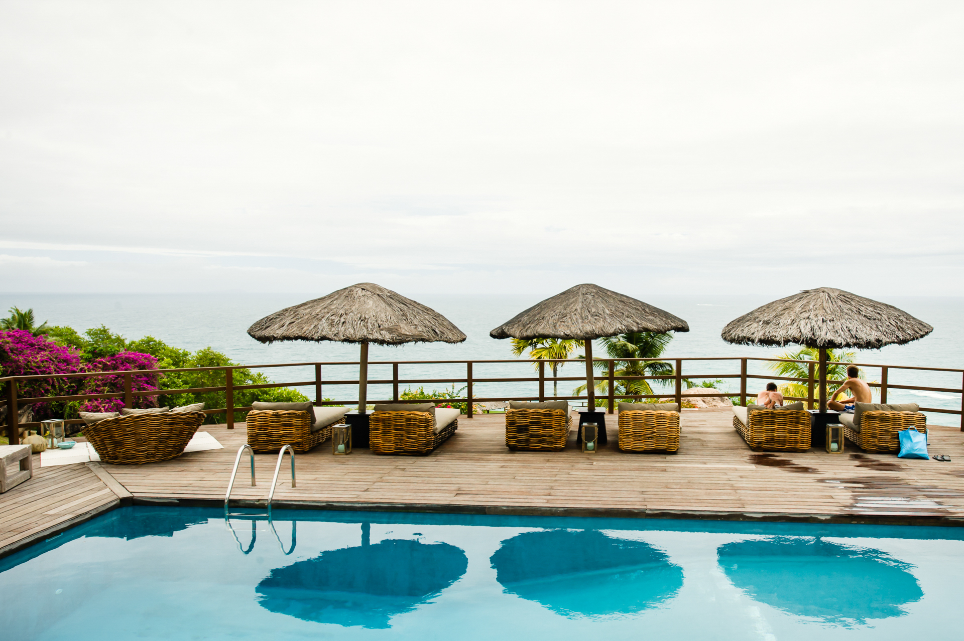 Fotografia de casamento em Ilha de Praslin, Seychelles | O noivo e o irmão dão um tempo ao lado da piscina