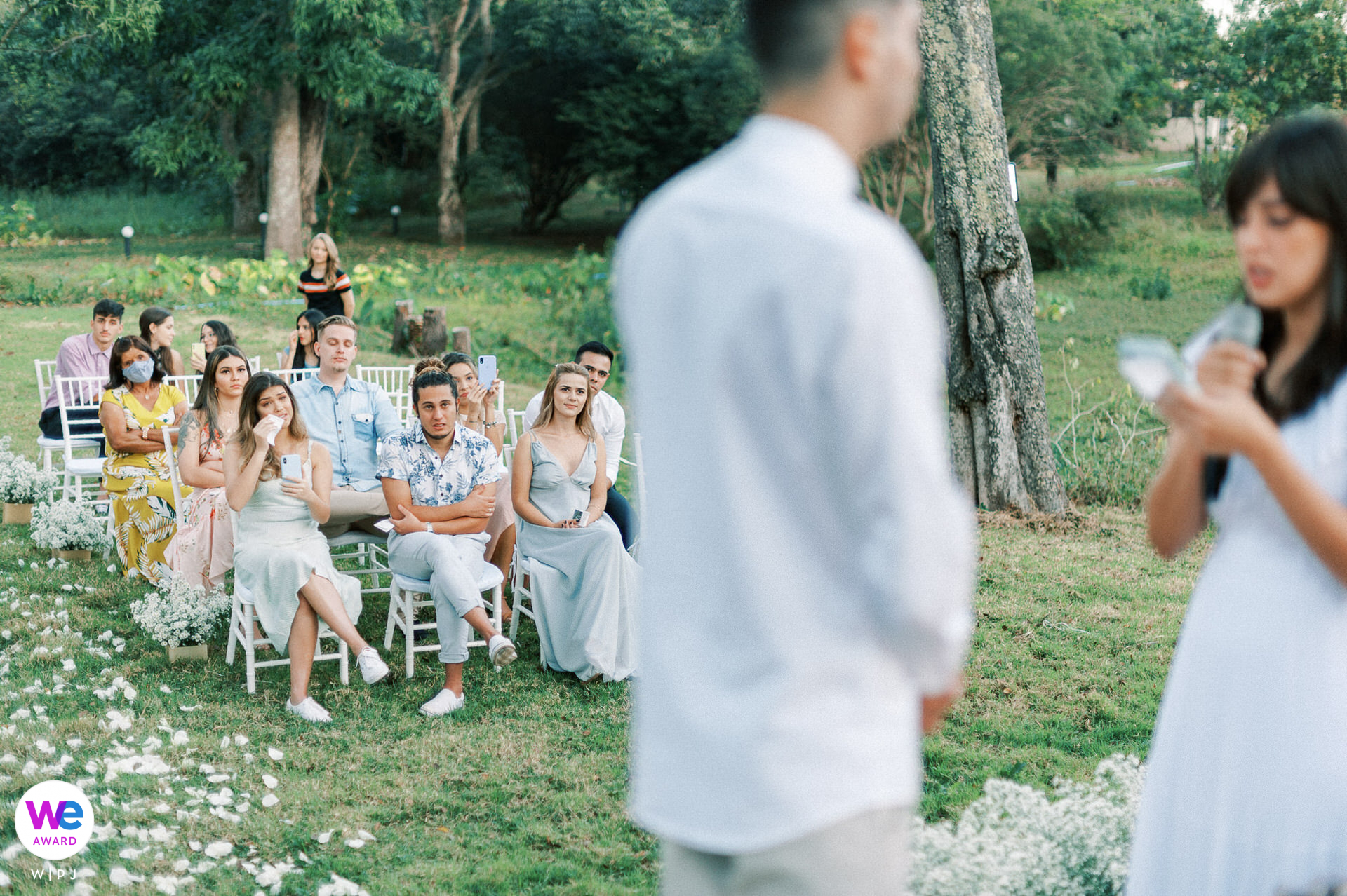 A cerimônia de casamento intimista dos noivos na fazenda particular foi uma bela vista, com convidados sentados em cadeiras na grama, completamente imersos no momento e emoções à flor da pele