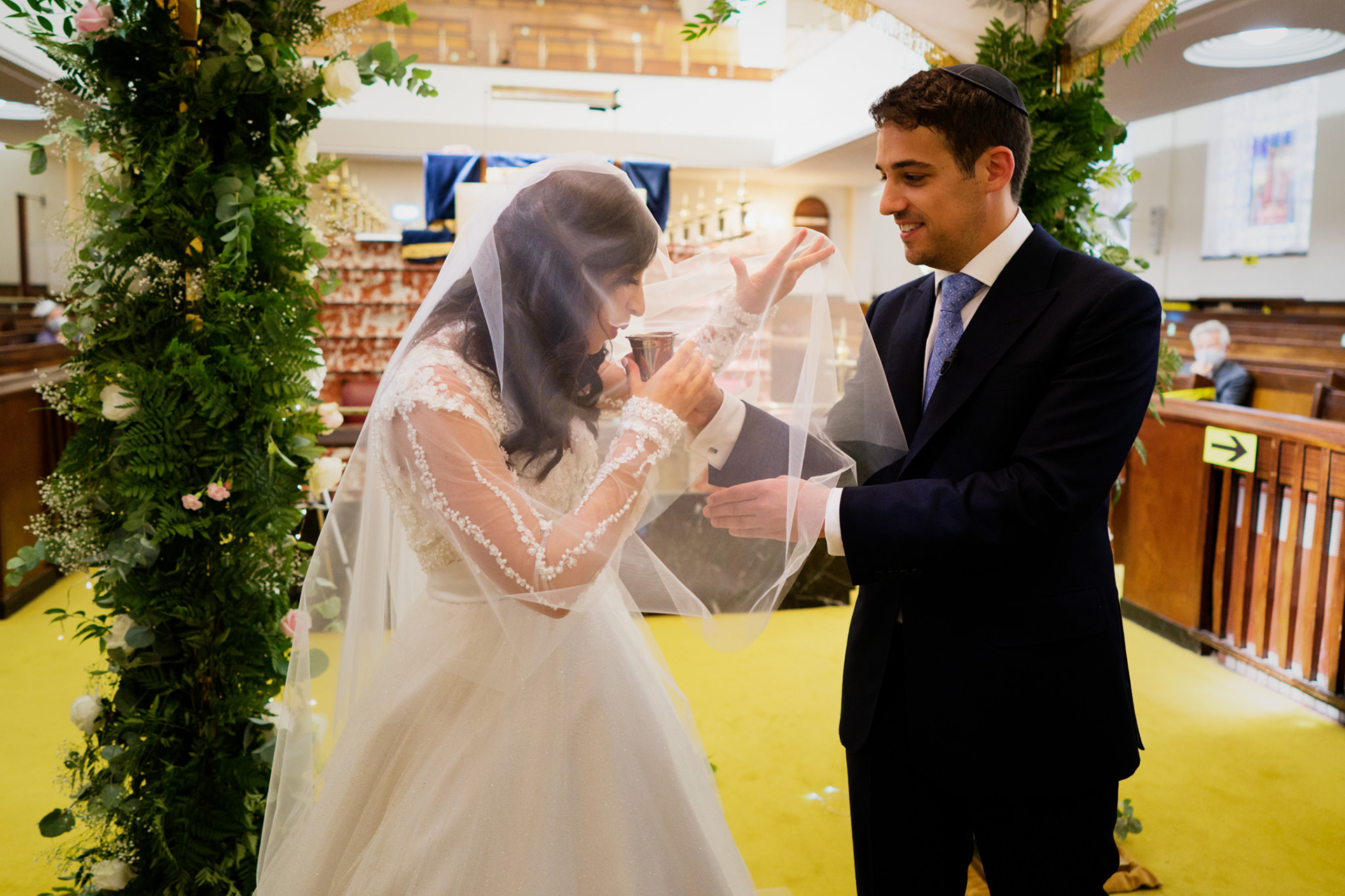 Gran Sinagoga, Fotógrafo de Elopement de Londres | El novio sostiene la copa de vino y se la ofrece a su novia.