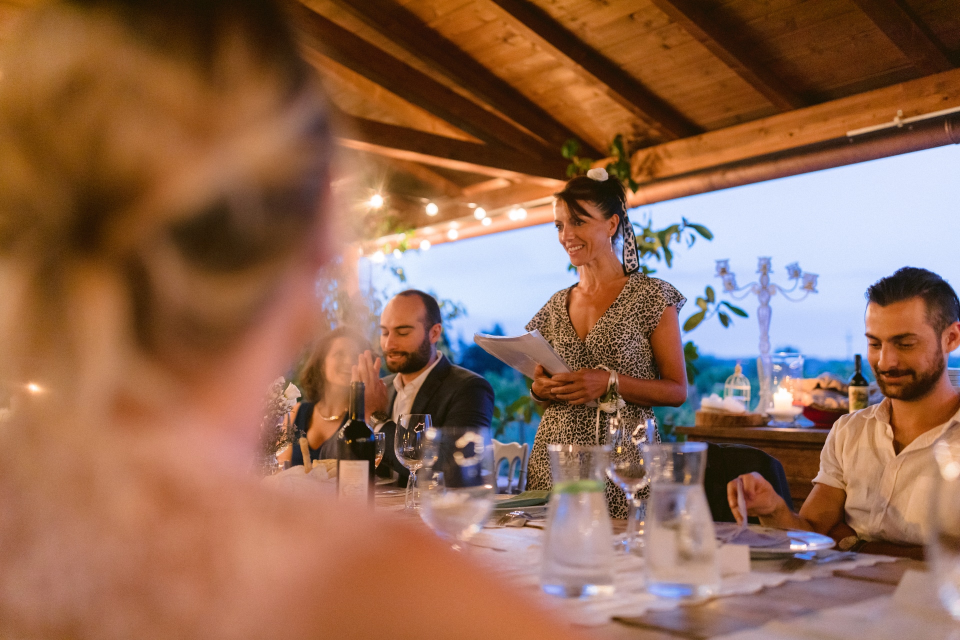 Image du lieu de réception en Toscane d'un élopement en Italie - Un invité au mariage prononce un discours Barberino di Mugello Comune en Italie Mariage Image | Discours d'un dîner de réception à Il Paese del Campanelli