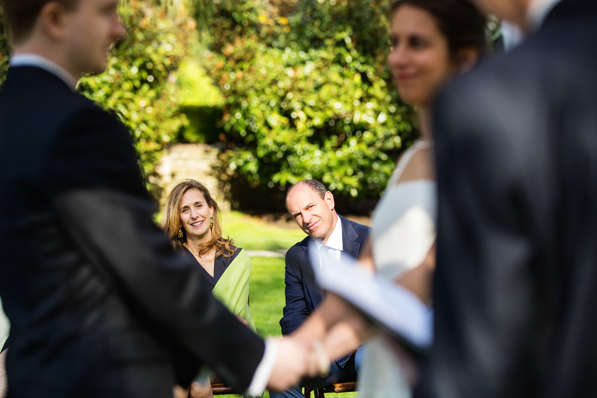 Het paar staat, hand in hand, terwijl de ouders van de bruid zijn ingelijst, getuige van de ceremonie op het Appleford Estate in Villanova, PA