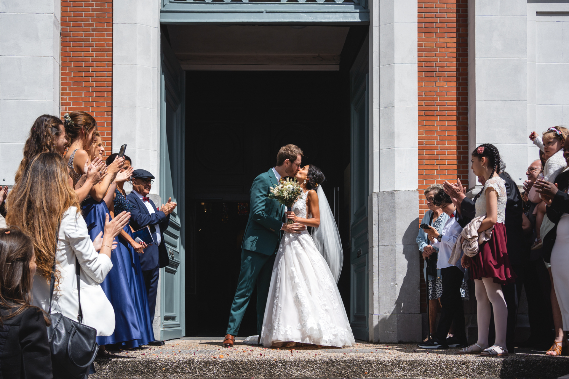 The joyous newlyweds as they kiss under the sunny skies outside the beautiful church in Lille.