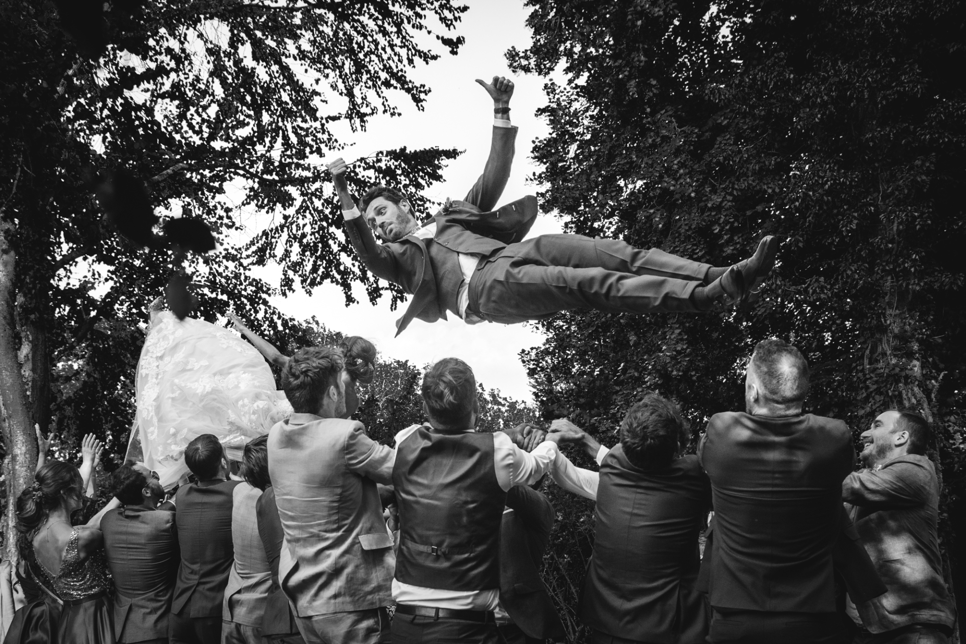 The joy of a wedding day, captured in one image as loved ones toss the happy couple into the air at Ferme des Templiers.