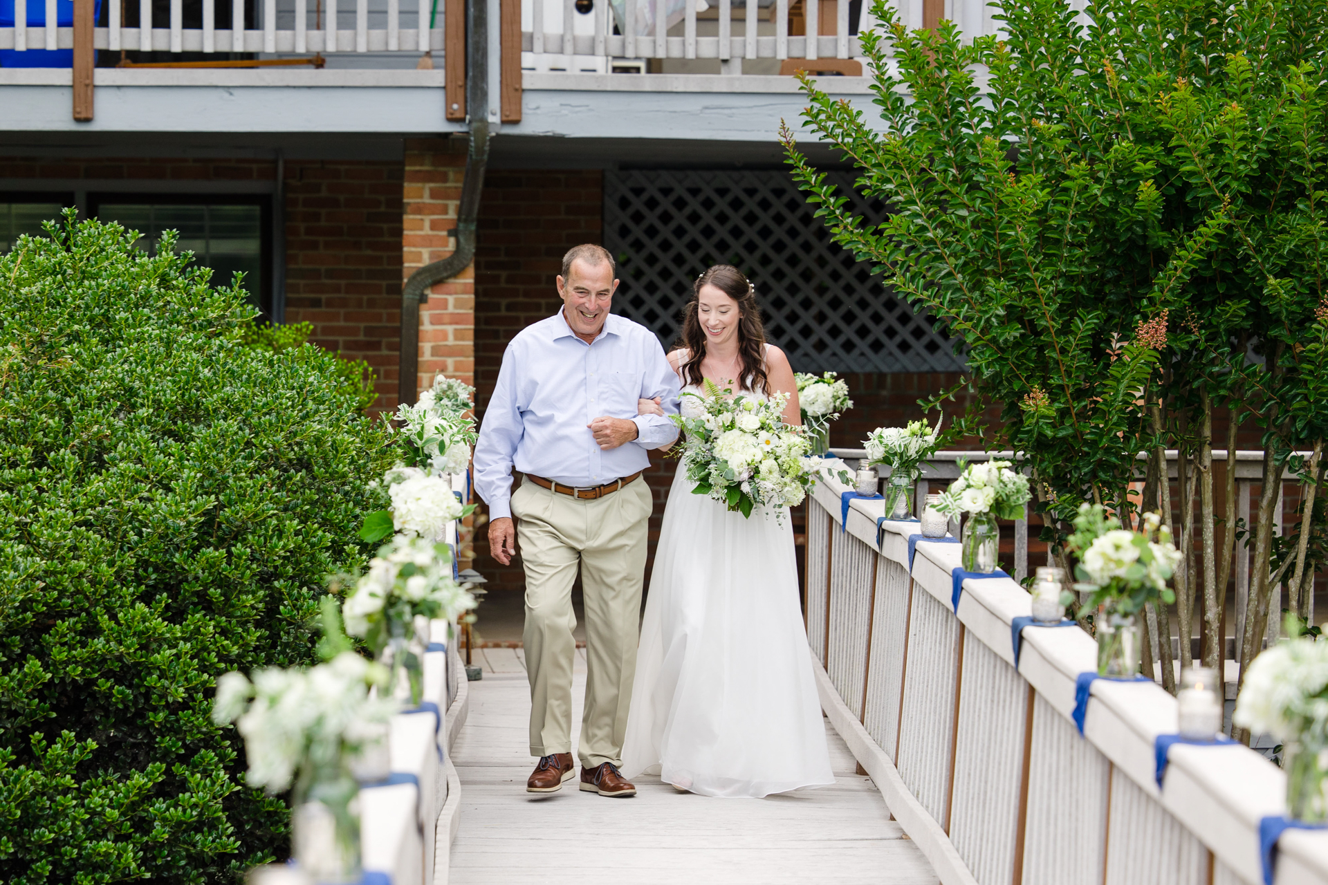 Bride and father walk gracefully down ramp to lakeside deck at Smith Mountain Lake.