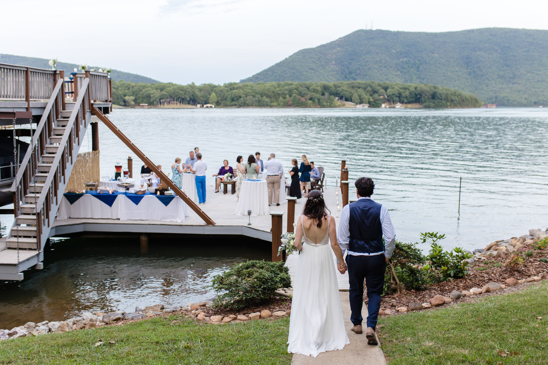 Wedding couple joyfully enters reception under deck where ceremony occurred, on multi-level structure.