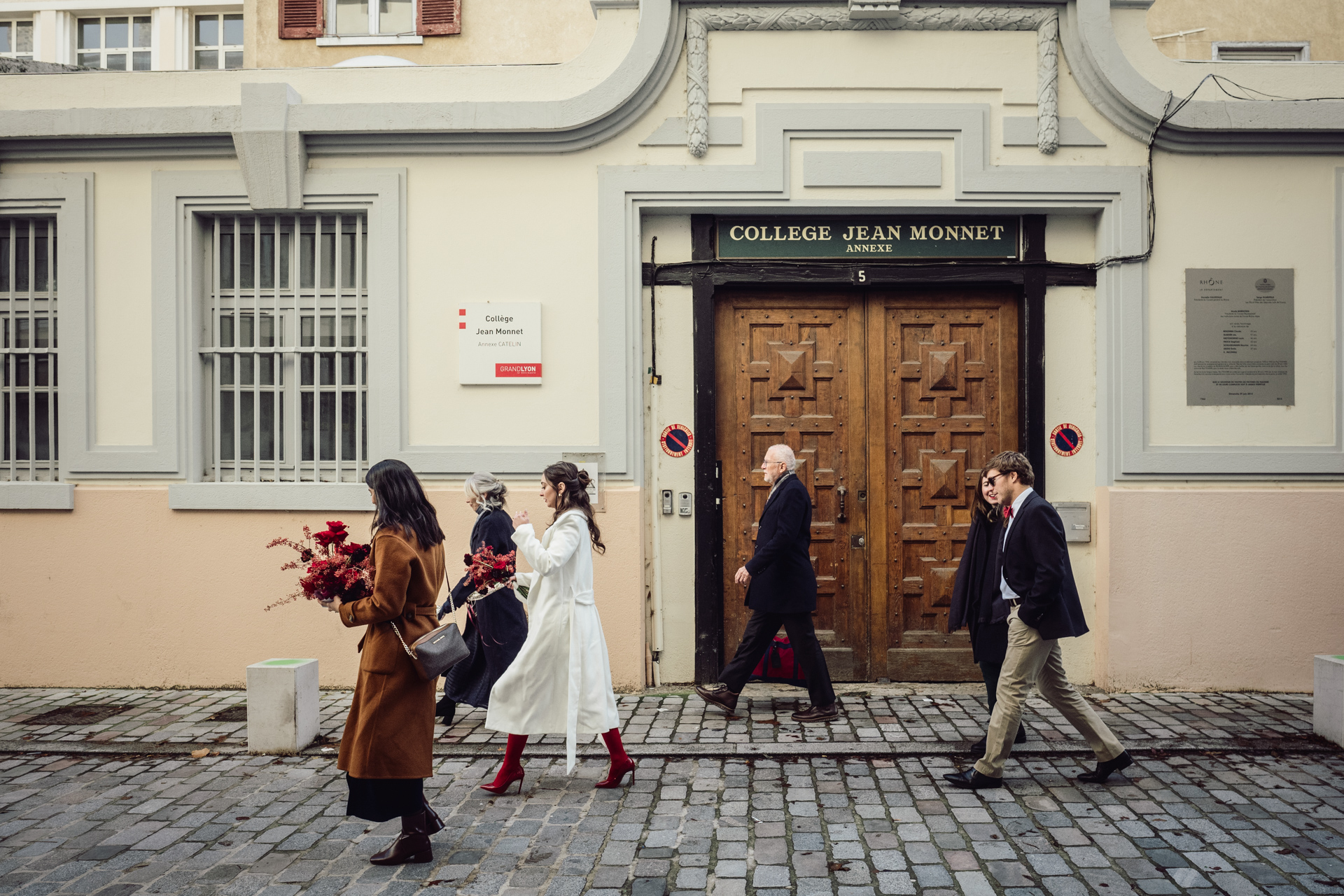 Guests stroll down a picturesque Lyon cobbled street toward a charming restaurant after intimate ceremony.