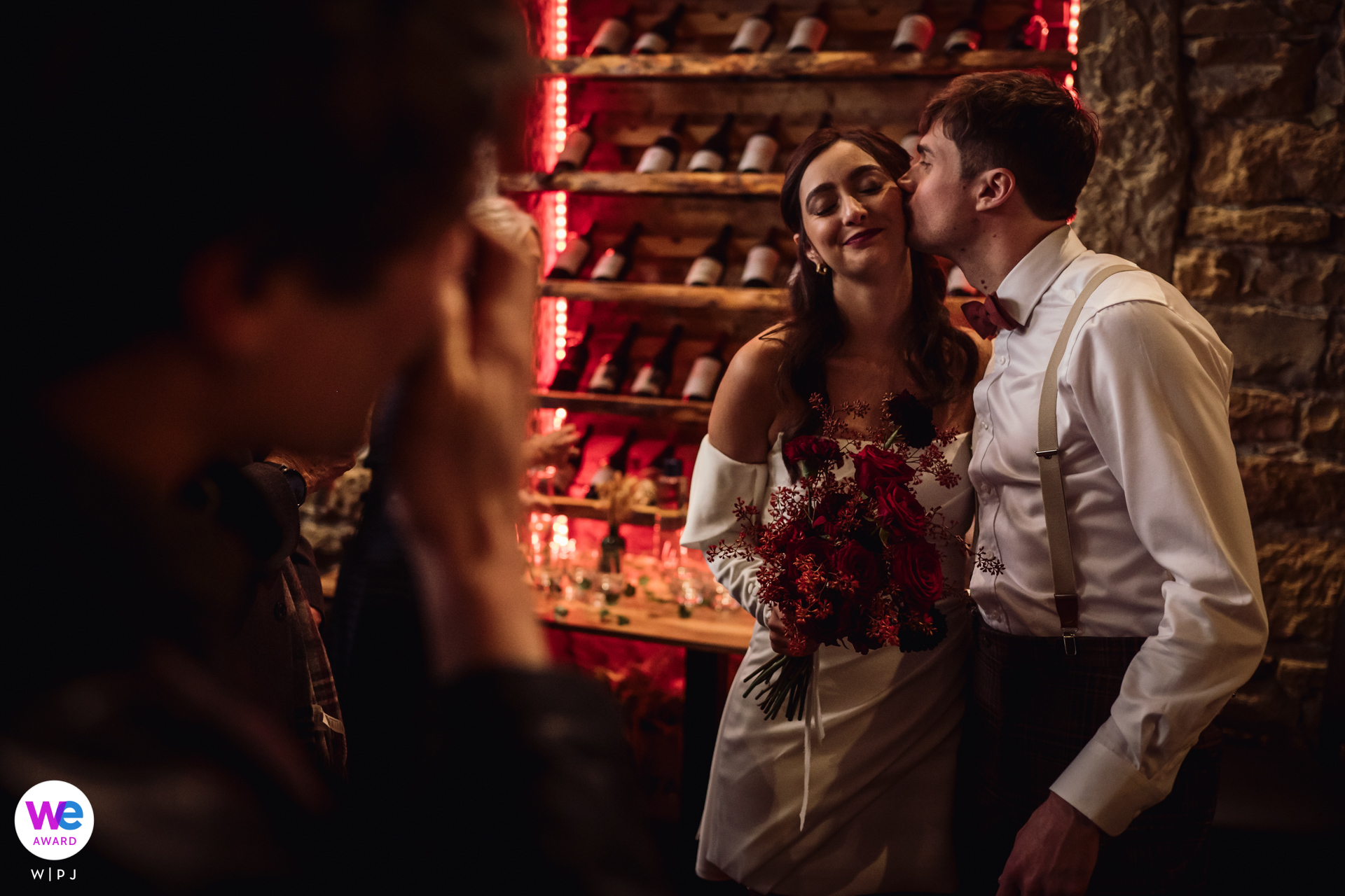 Couple shares a secret kiss, embraced in warm light inside an intimate gastronomic restaurant evening.